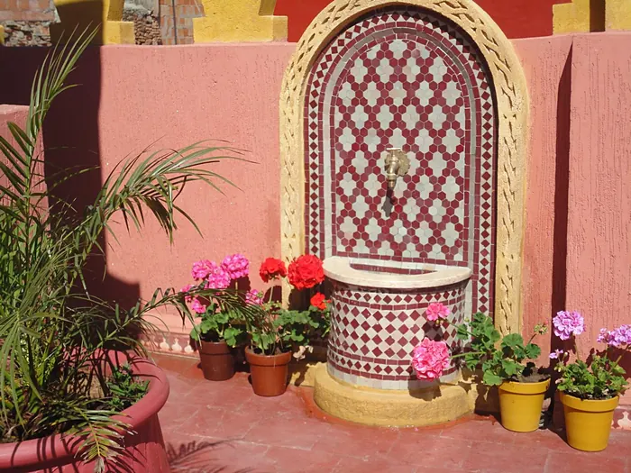 La fontaine murale de la terrasse et ses géraniums